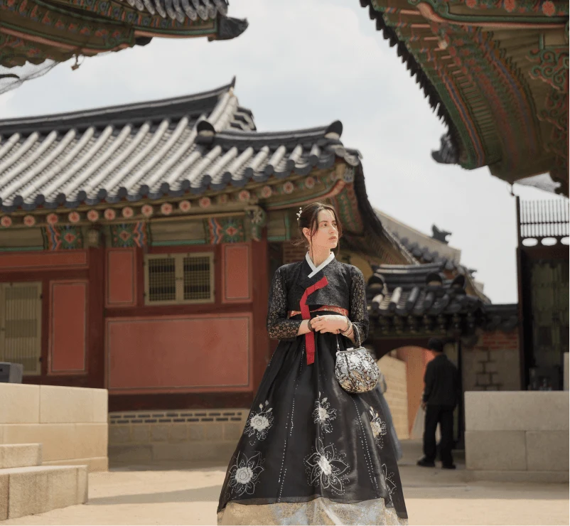 A traveler in a black hanbok in a palace courtyard