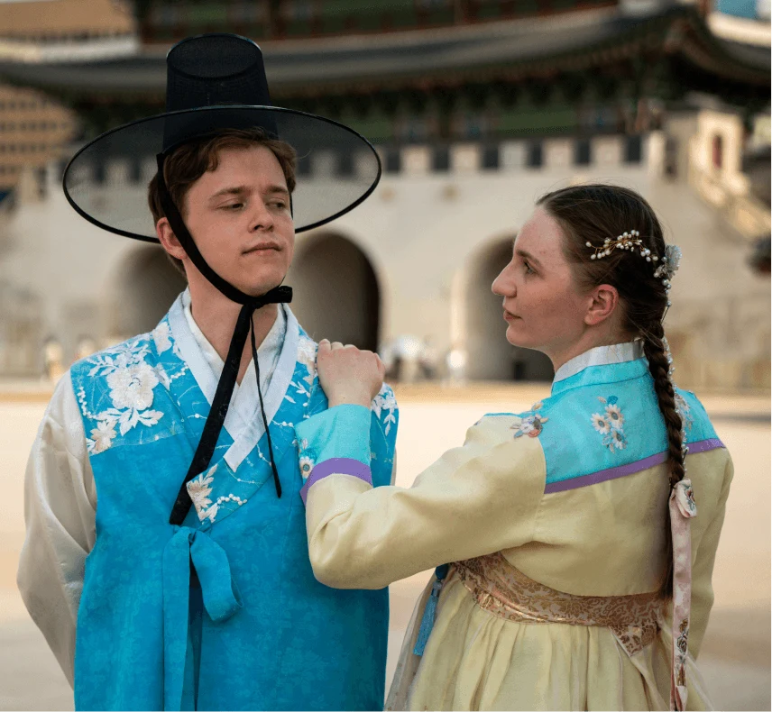 Two tourists in traditional Korean clothing near a palace