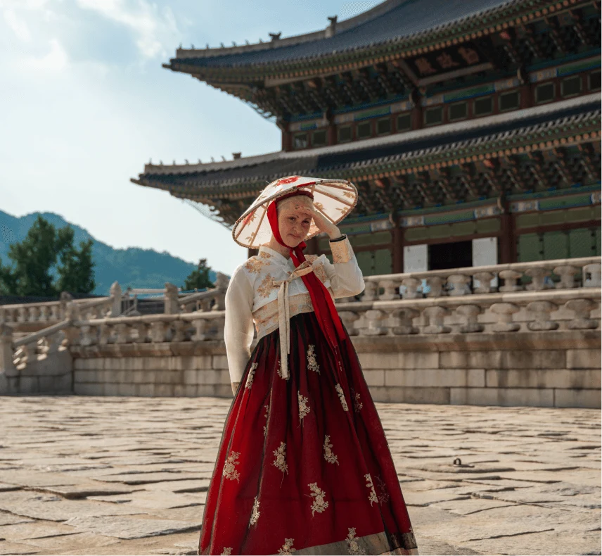 A traveler in a red-and-white hanbok at a palace