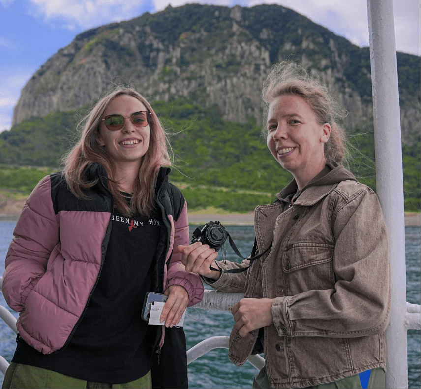 Two travelers with a camera on a boat off a mountainous coast