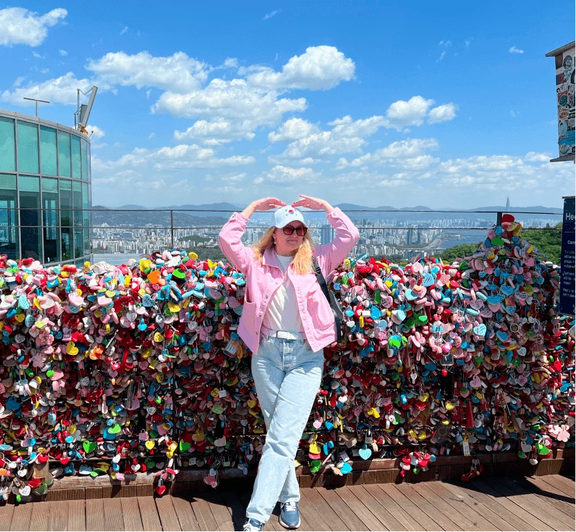 A traveler by a wall of love locks overlooking the city and the sea