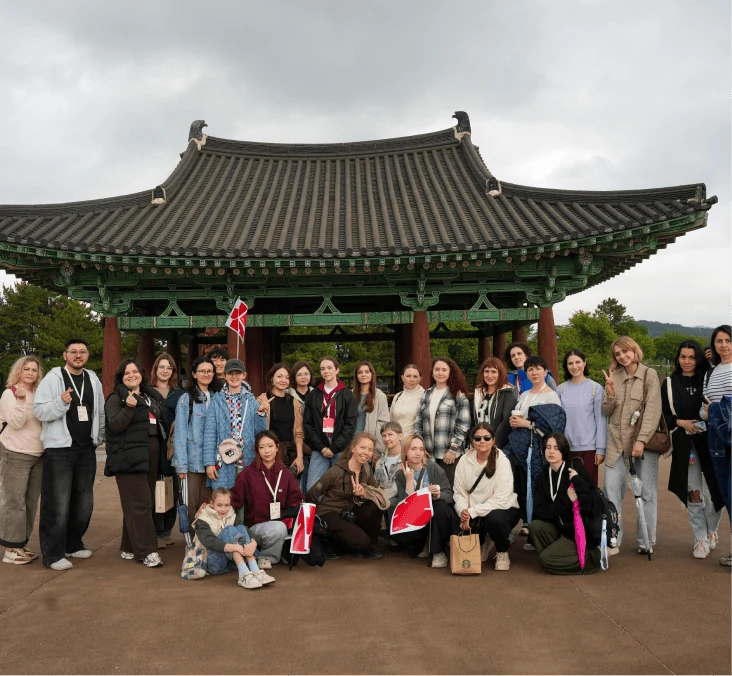 A large group of travelers in front of a traditional pavilion