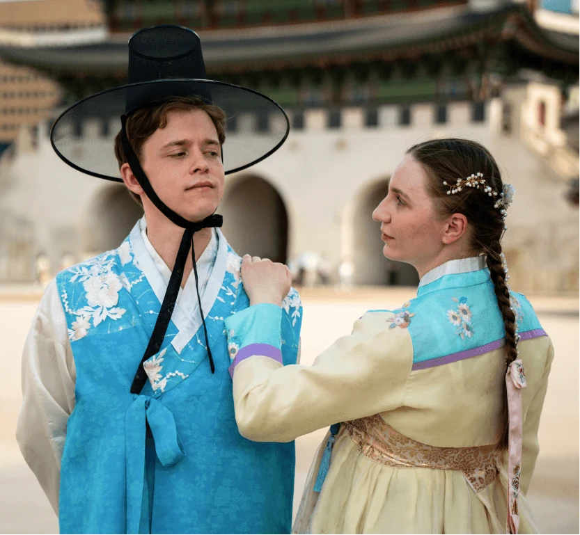 Two tourists in traditional Korean clothing near a palace