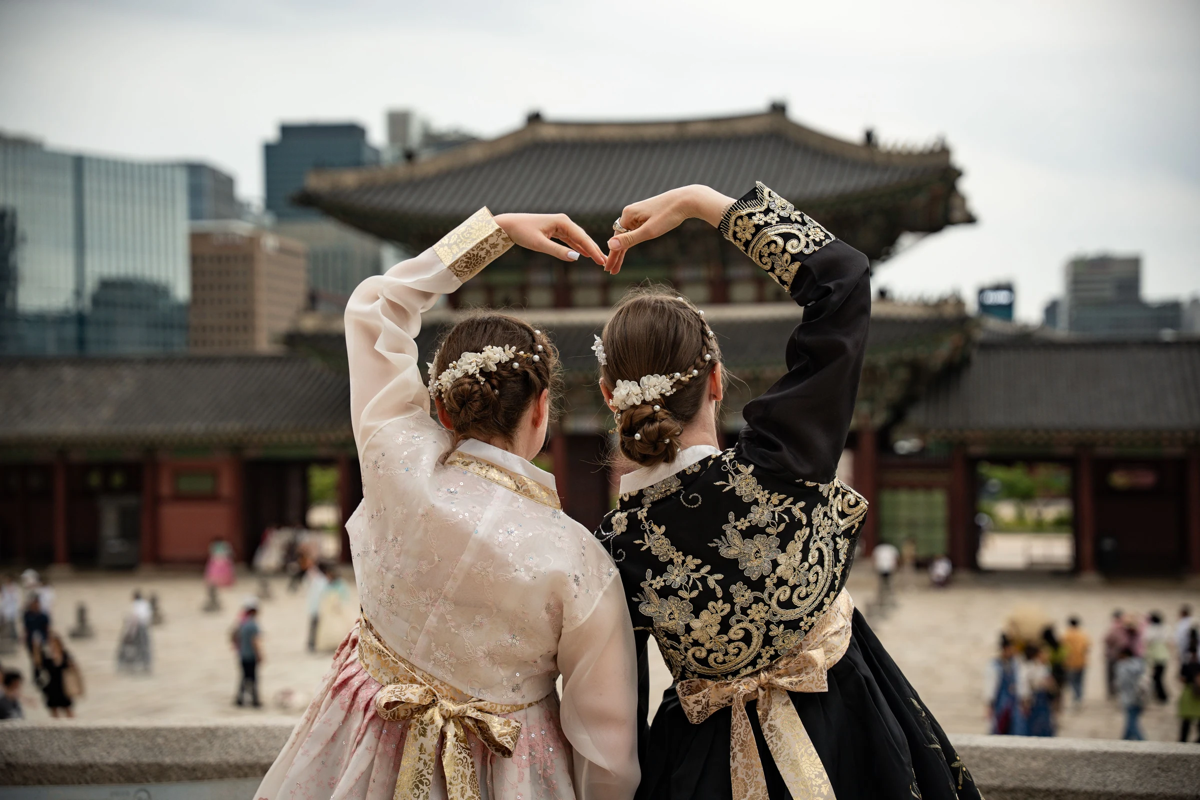 Two travelers in hanbok, seen from behind, at a palace
