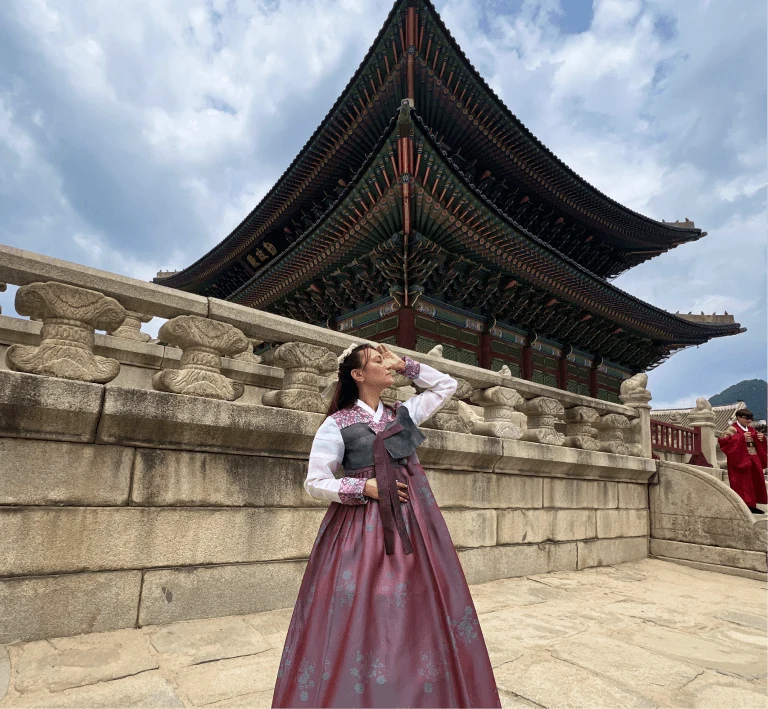 A traveler in a pink hanbok by the palace