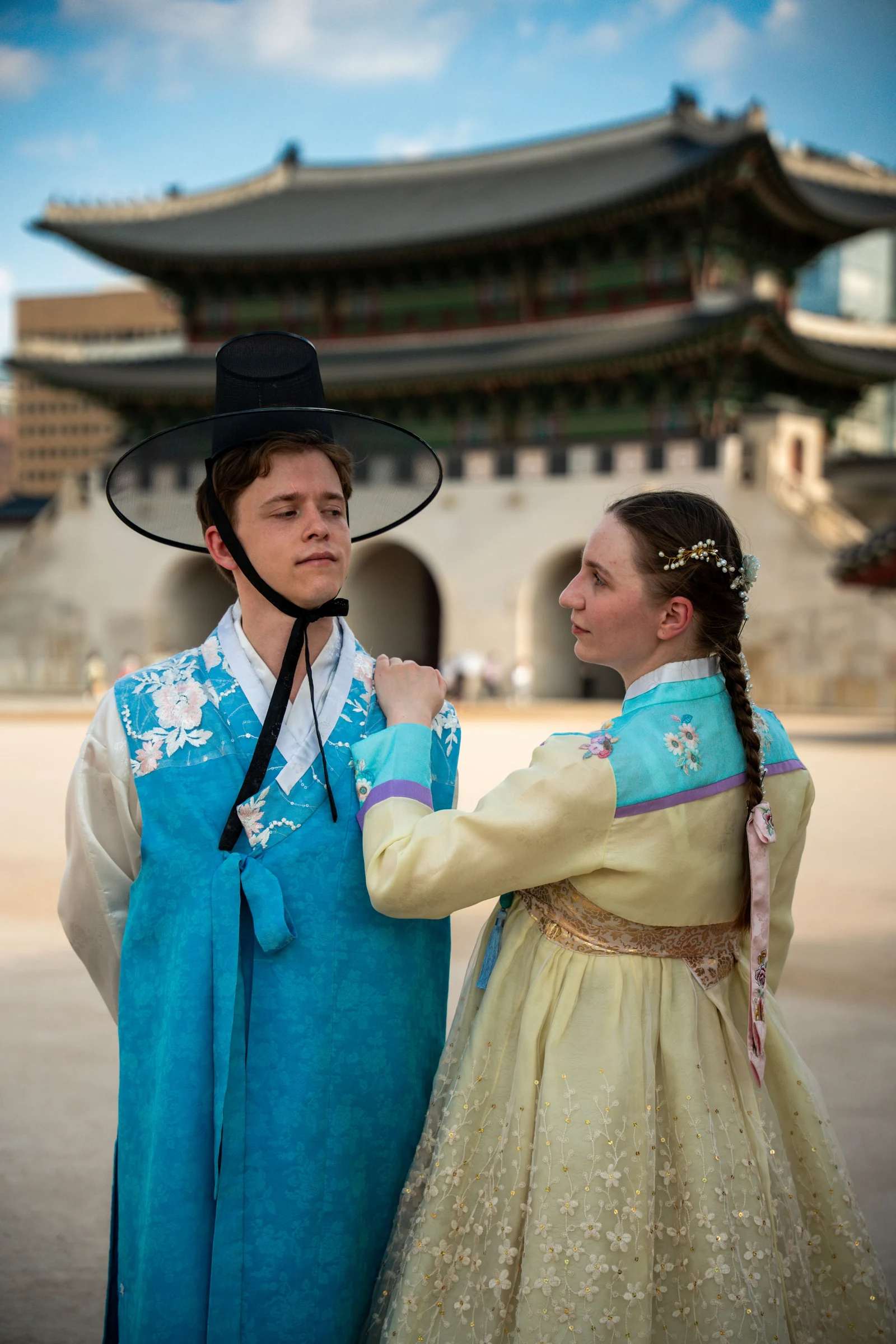 Two tourists in traditional Korean clothing near a palace