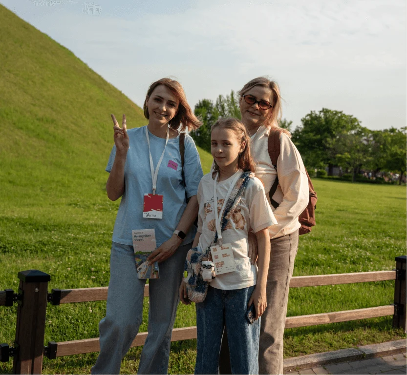 Three travelers by a green hill